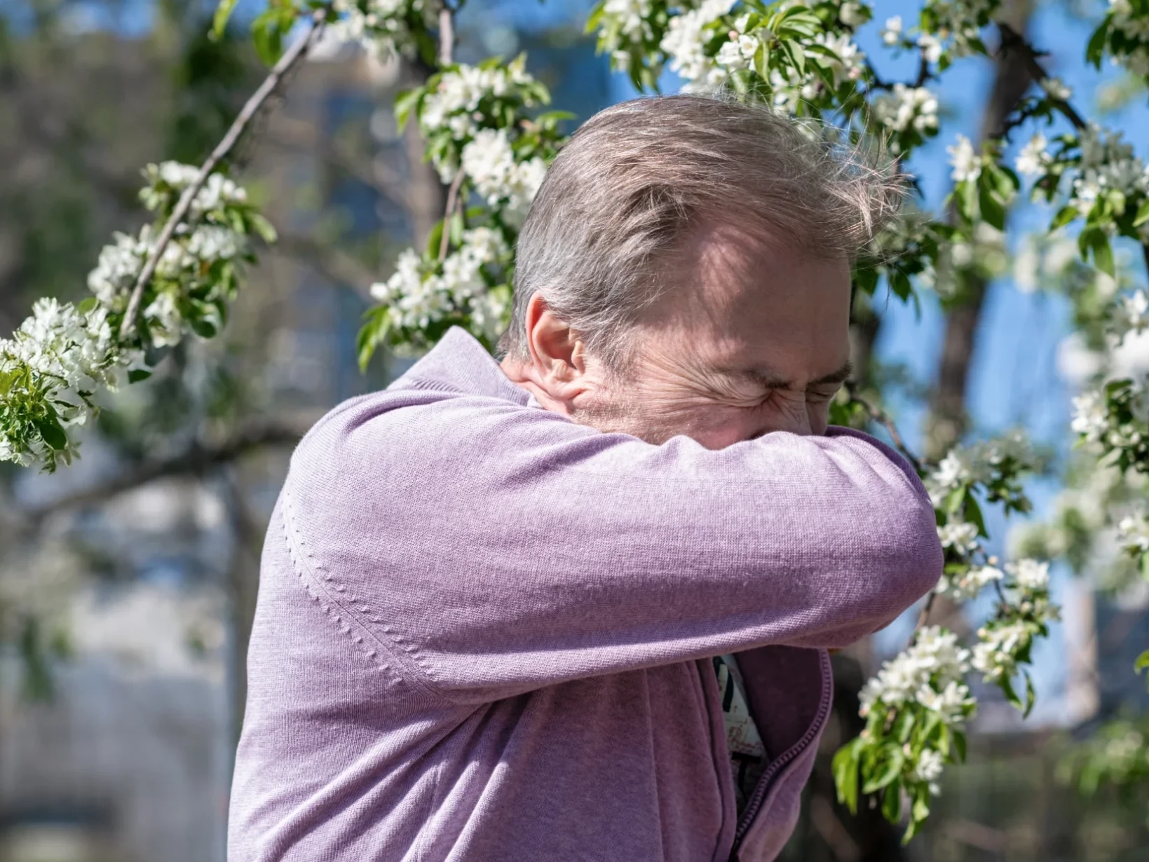 Ein Mann in der Natur niest in die Armbeuge