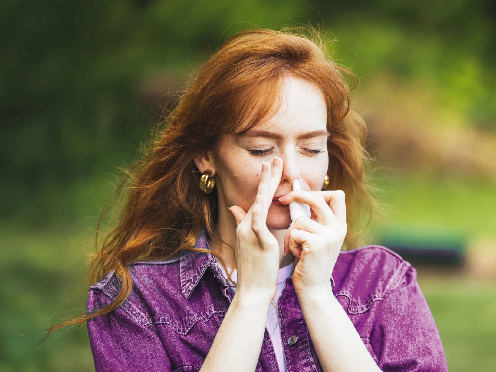 Eine Frau benutzt draußen im Park Nasenspray