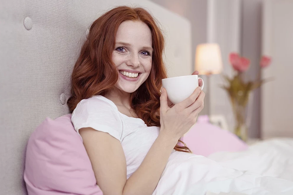 Frau mit Tasse Tee im Bett